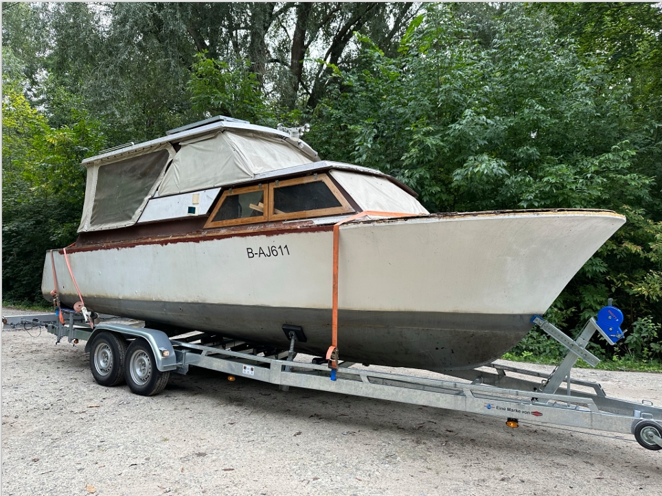 Ein Traktor zieht ein Boot auf einem Anhänger und veranschaulicht den Transport des Bootes zu einem nahegelegenen Wasserweg.